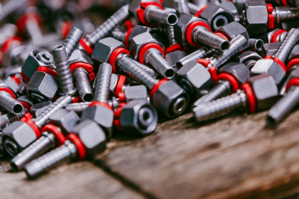 Ein Stapel Metallbolzen mit roten und schwarzen Gummiringen auf einer Holzoberfläche, der industrielle Hardwarekomponenten zur Schau stellt.
