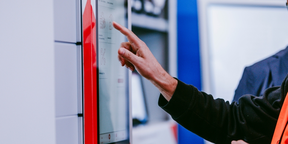 Hand, die Touchscreen eines Ausgabeautomaten berührt