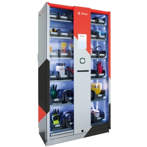 Ein Wiegezellenautomat mit mehreren Regalfächern, in denen verschiedene Artikel aufbewahrt werden. Die Regale enthalten kleine weiße Behälter, und im unteren Fach befinden sich zwei größere Behälter mit blauer und weißer Etikettierung. In der Mitte des Automaten befindet sich eine vertikale graue Bedieneinheit mit einem Bildschirm und einem runden Knopf.
