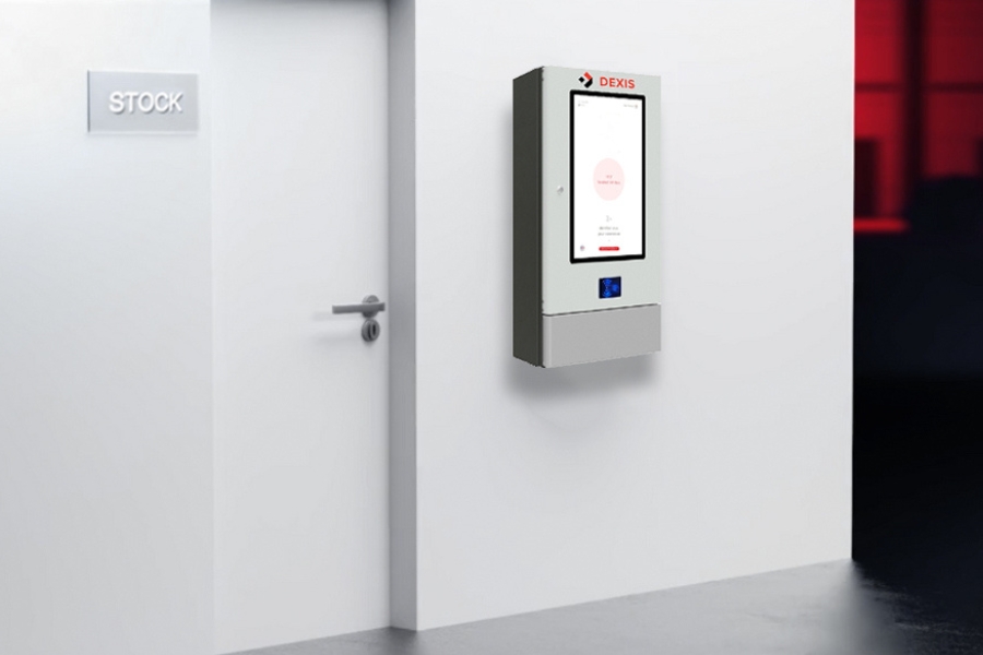 Lagerverwaltungsautomat häng an einer Wand neben einer Tür die in einem Lagerraum führt. Die Tür des Lagerraums ist geschlossen.