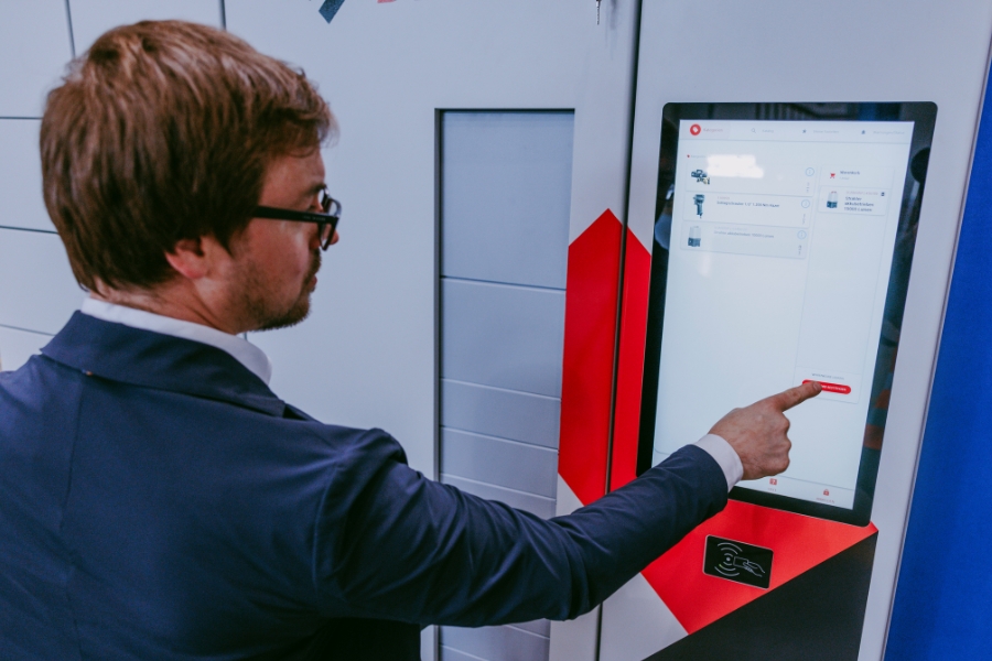 Mann drückt Button auf dem Display von einem Ausgabeautomaten