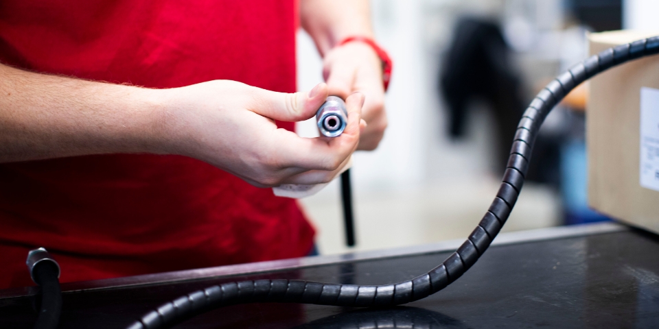 Hände die einen Hydraulikschlauch halten